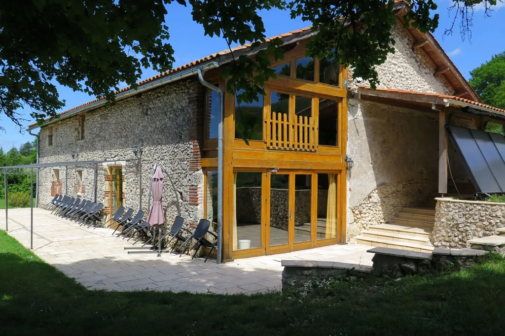 Façade du gîte avec grande terrasse ombragée donnant sur la vallée