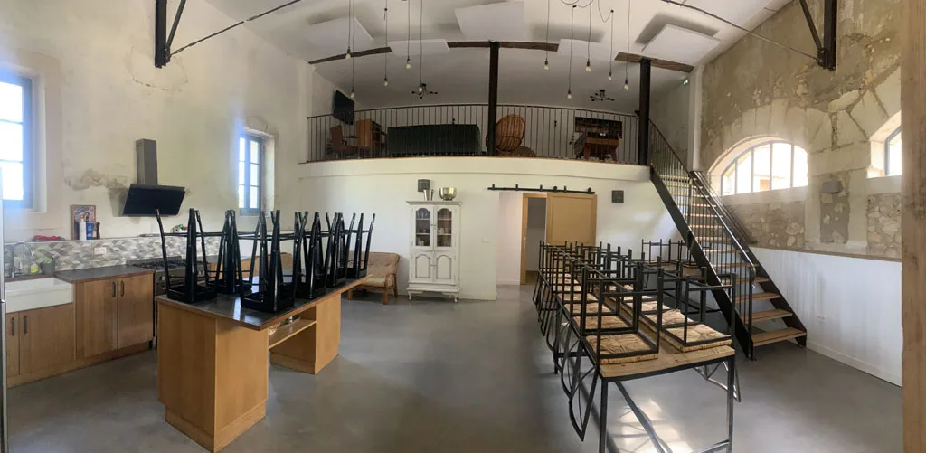 Grande salle de réception aux poutres apparentes avec tables et mezzanine