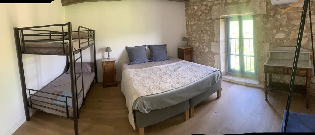 Chambre avec lit double, poutres et fenêtre sur la campagne