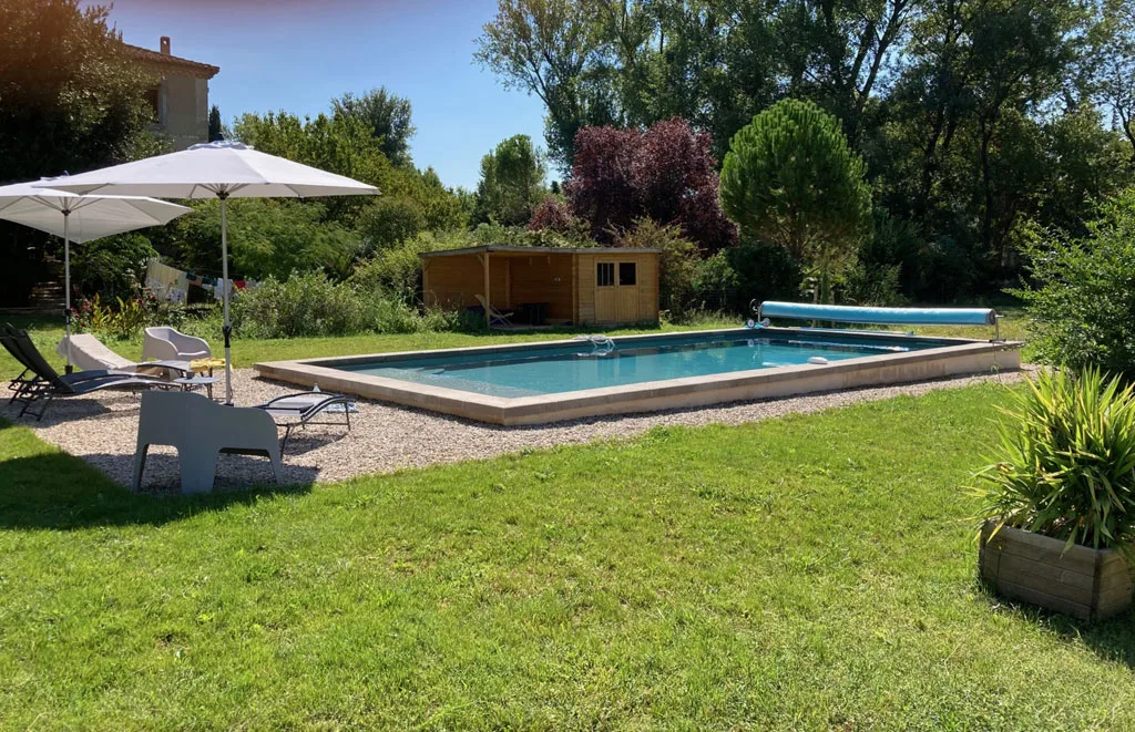 Piscine de 5x11 m avec pelouse et transats devant le mas en pierre