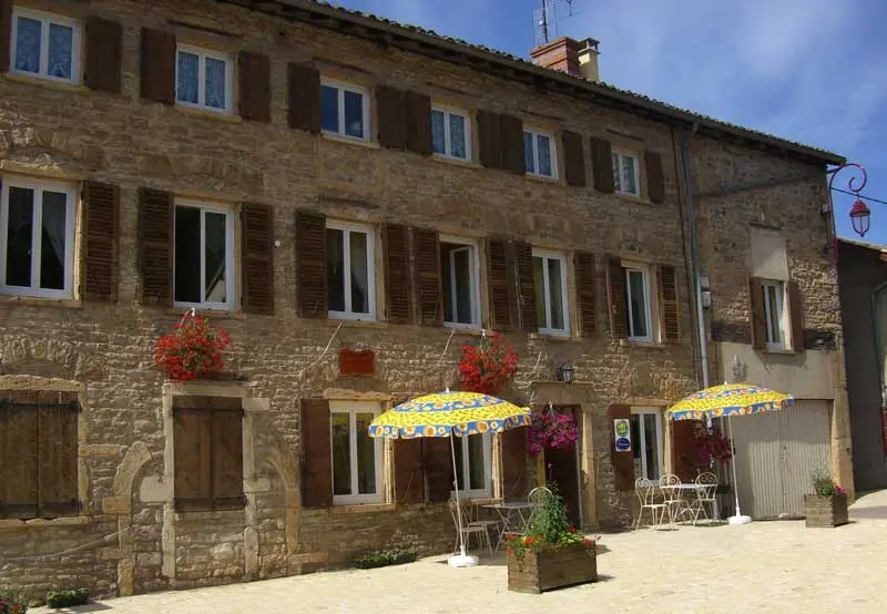 Grande maison en pierres du village avec terrasses ombragées et volets en bois