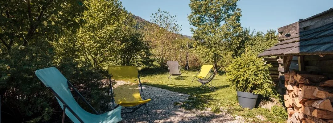 Terrasse ombragée du gîte Lanchette avec tables et chaises en bois pour les repas