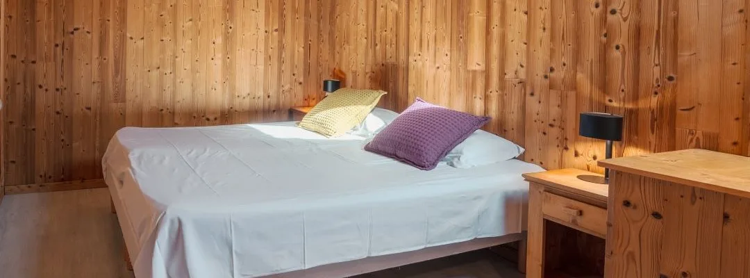Chambre lumineuse du gîte Lanchette avec deux lits et décoration chalet