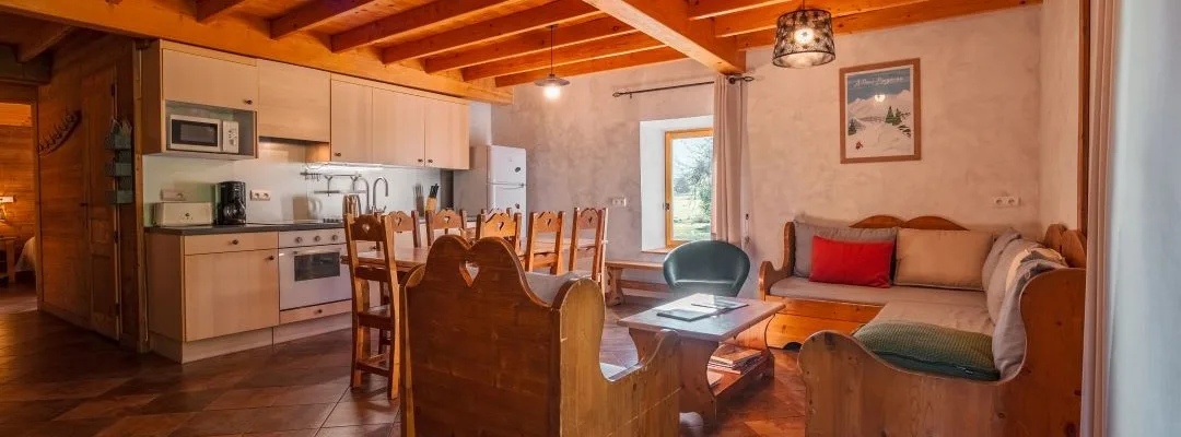 Séjour chalet Rochette avec cuisine ouverte, poutres apparentes et grande table en bois