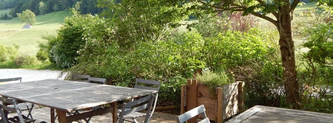 Terrasse en bois avec grande table conviviale et vue dégagée sur la vallée verdoyante