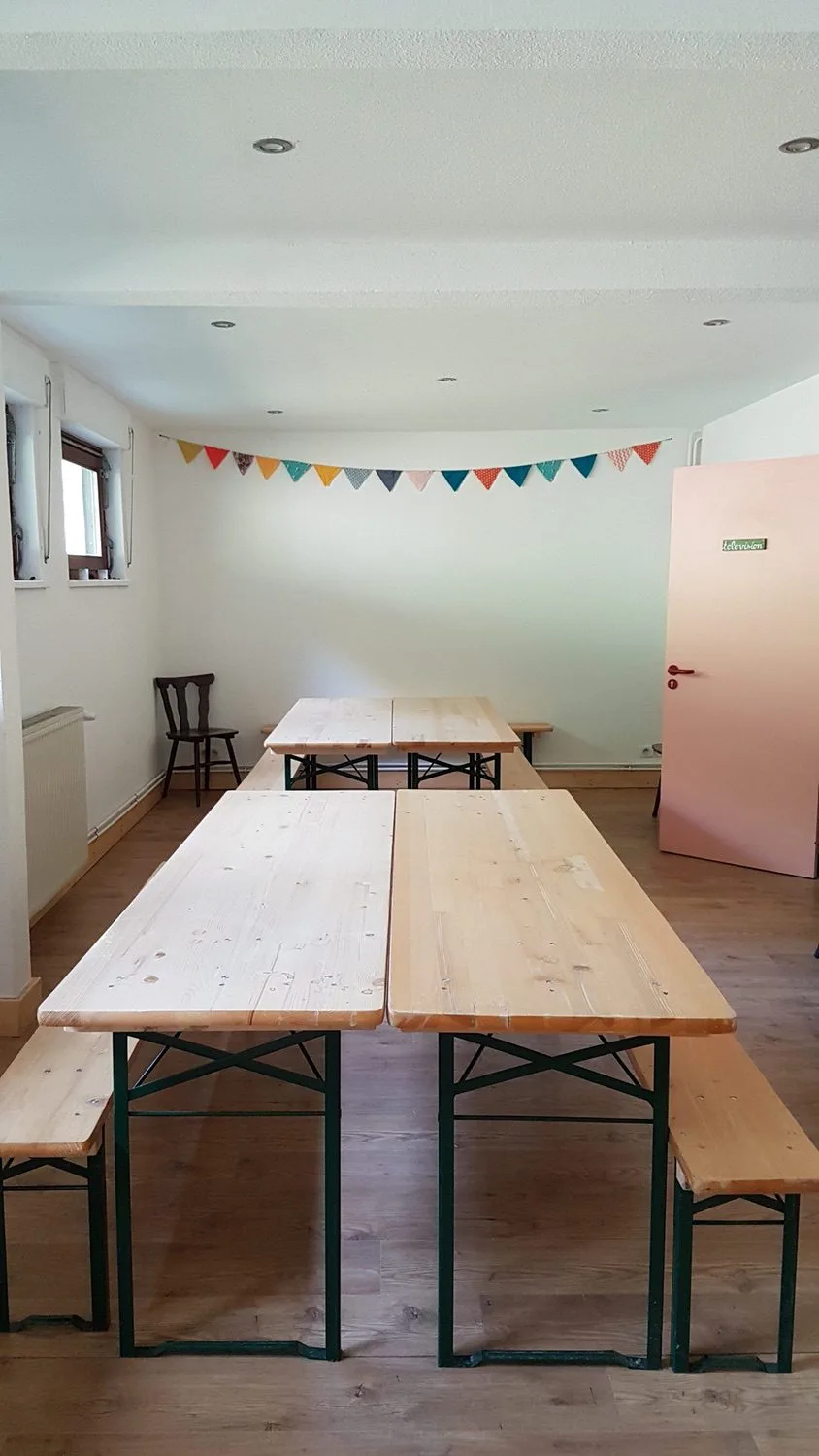 Grande salle commune avec tables et bancs façon brasserie pour repas de groupe