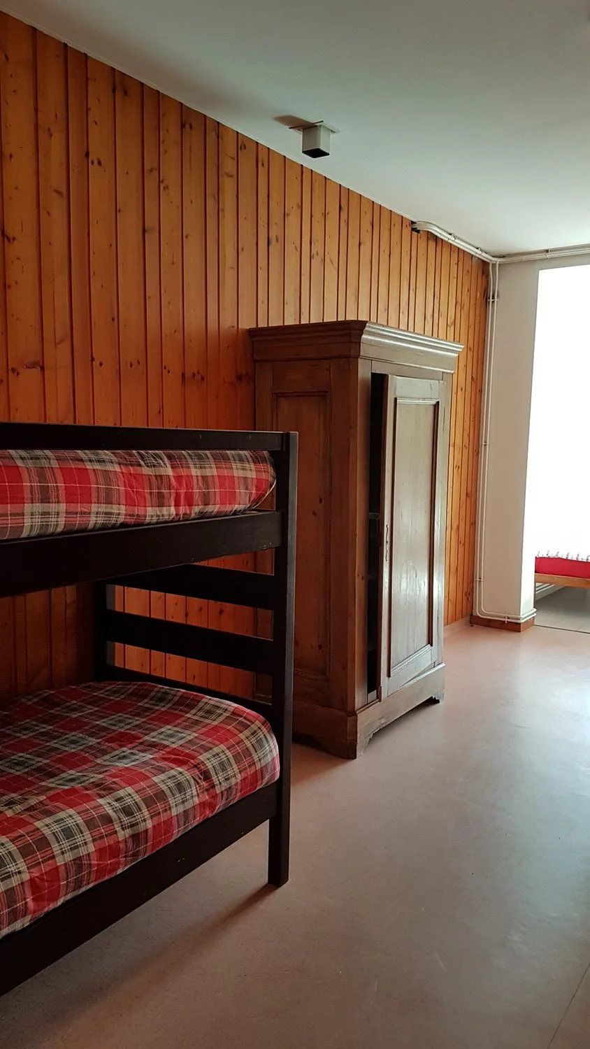 Chambre avec lits superposés en bois et armoire ancienne