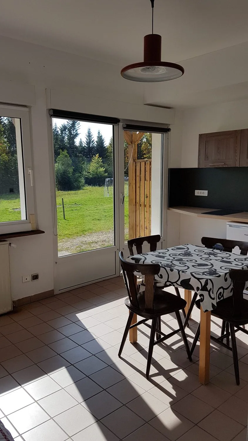 Cuisine ouverte avec coin repas, table et vue sur la prairie environnante