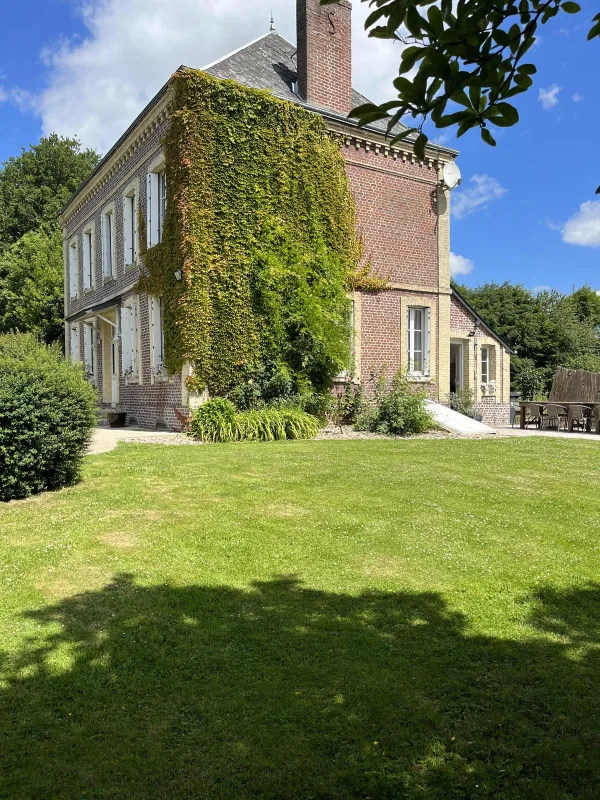 Façade en briques couverte de lierre de La Familiale, entrée principale du gîte