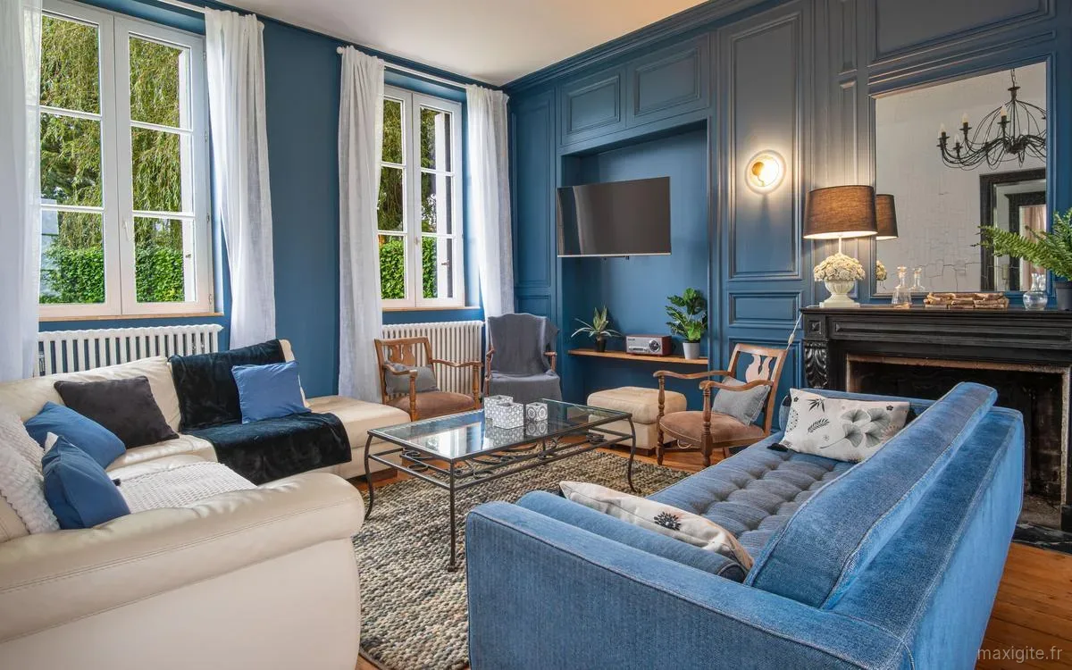Salon bleu avec cheminée en pierre, canapés et ambiance chaleureuse