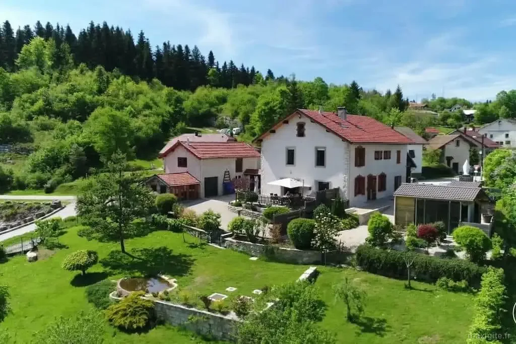 Vue d'ensemble de la maison avec jardin et terrasse dans le Haut-Jura
