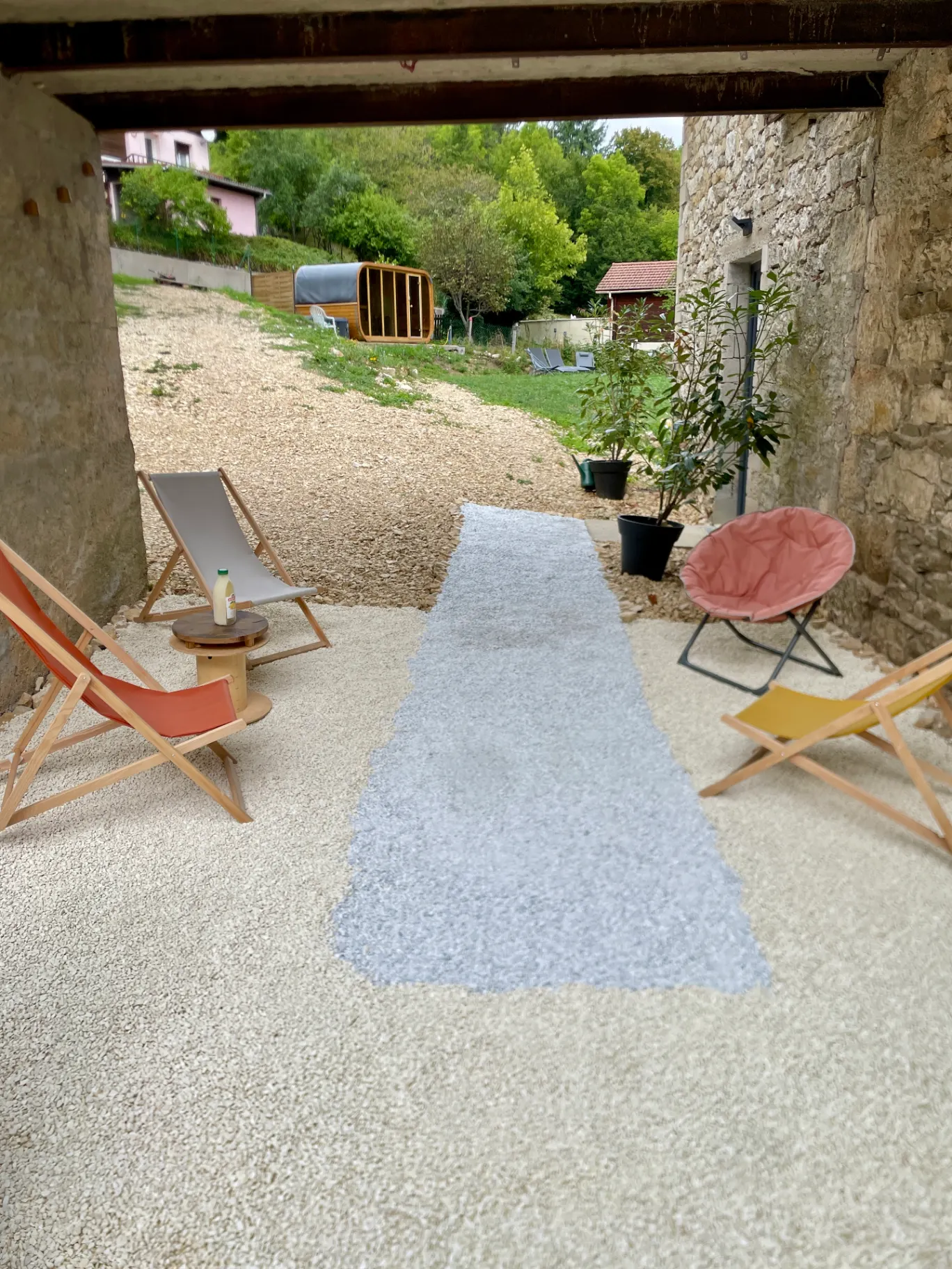 Patio extérieur avec table et chaises en bois, entouré de murs en pierre