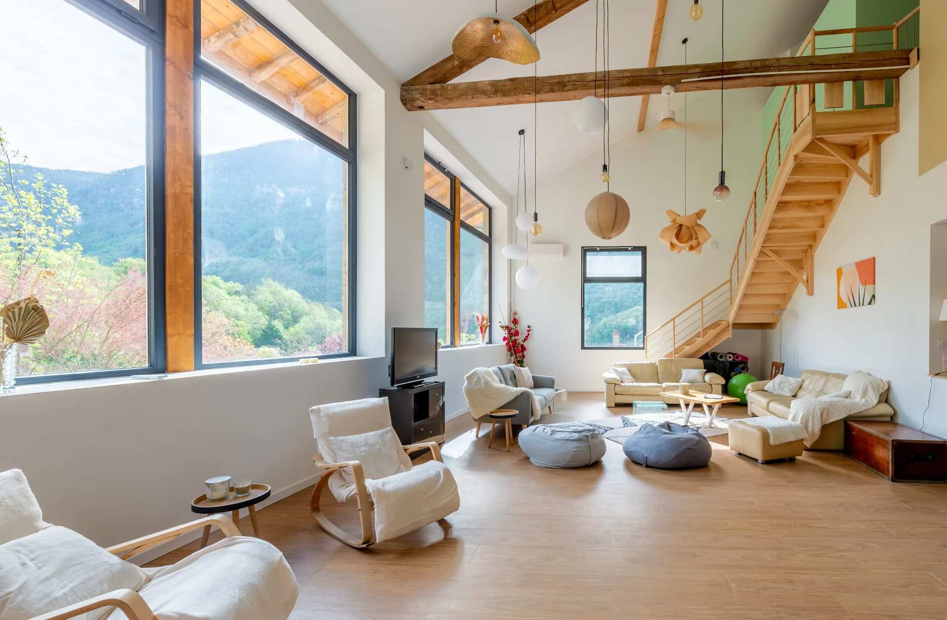 Salon cosy avec canapés, tapis et poutres apparentes sous mezzanine