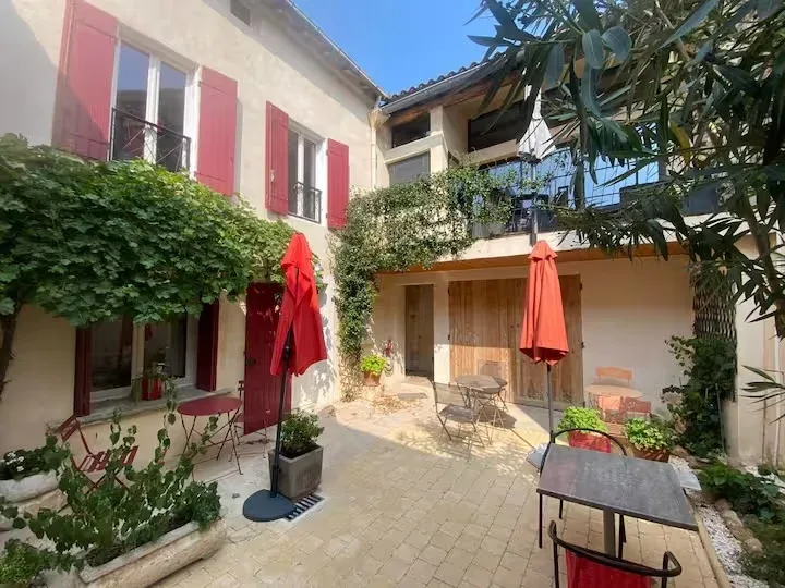 Gîte de groupe Instant en Provence à Eyragues — Façade du mas provençal avec volets rouges, cour intérieure pavée et terrasses, capacité 20 personnes