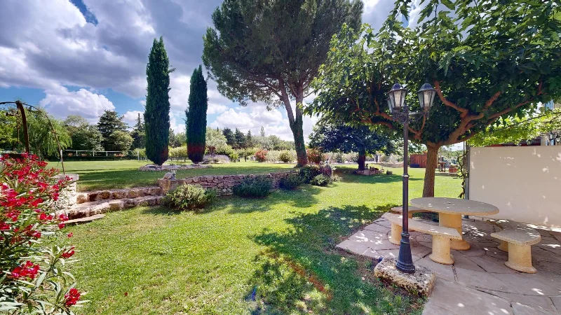 Grand jardin arboré avec table de pique-nique en pierre sous les arbres et pelouse verdoyante
