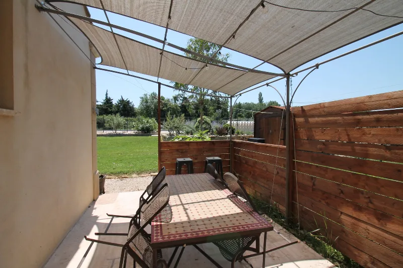 Terrasse ombragée sous une pergola en toile, table à manger extérieure et vue sur le jardin