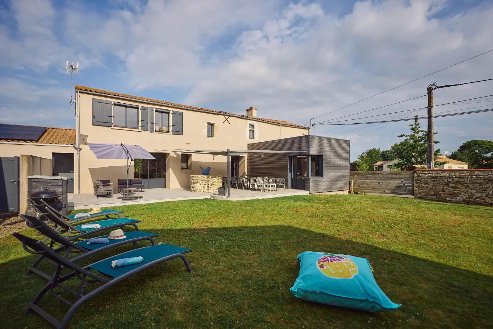 Gîte de groupe Domaine de la Coutardière à Saint-Vincent-sur-Jard — Façade arrière de la maison de ferme avec grand jardin, terrasse et transats sur la pelouse, capacité 15 personnes