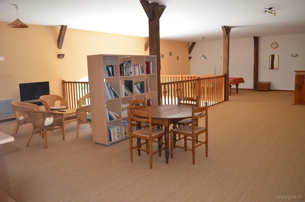 Coin bibliothèque et salon avec fauteuils en rotin près de la mezzanine