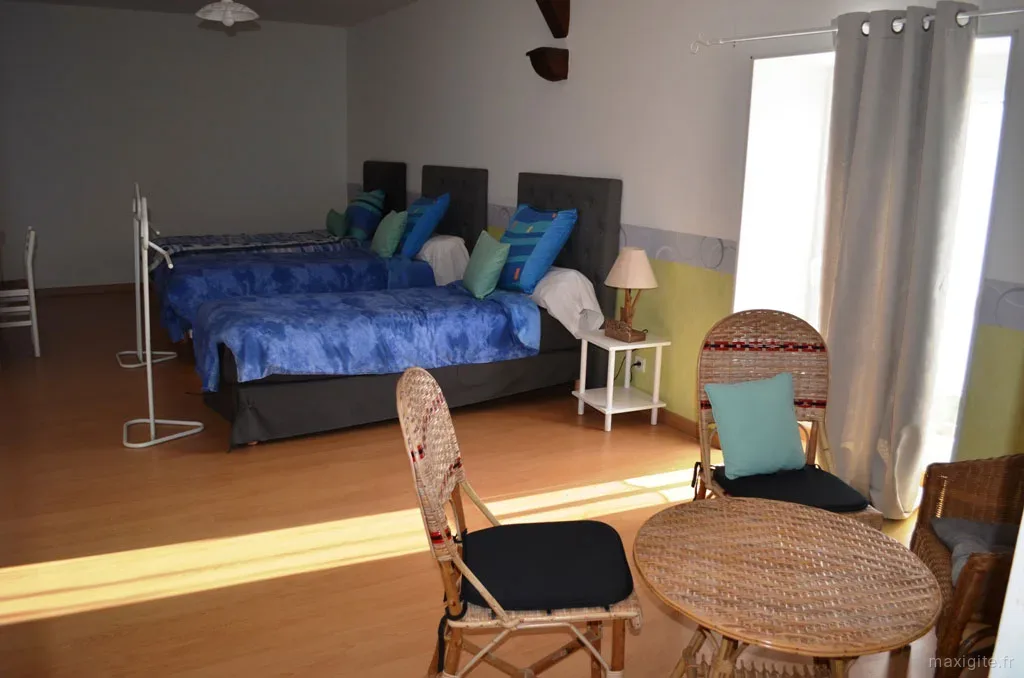 Chambre avec lit double et coin salon en rotin