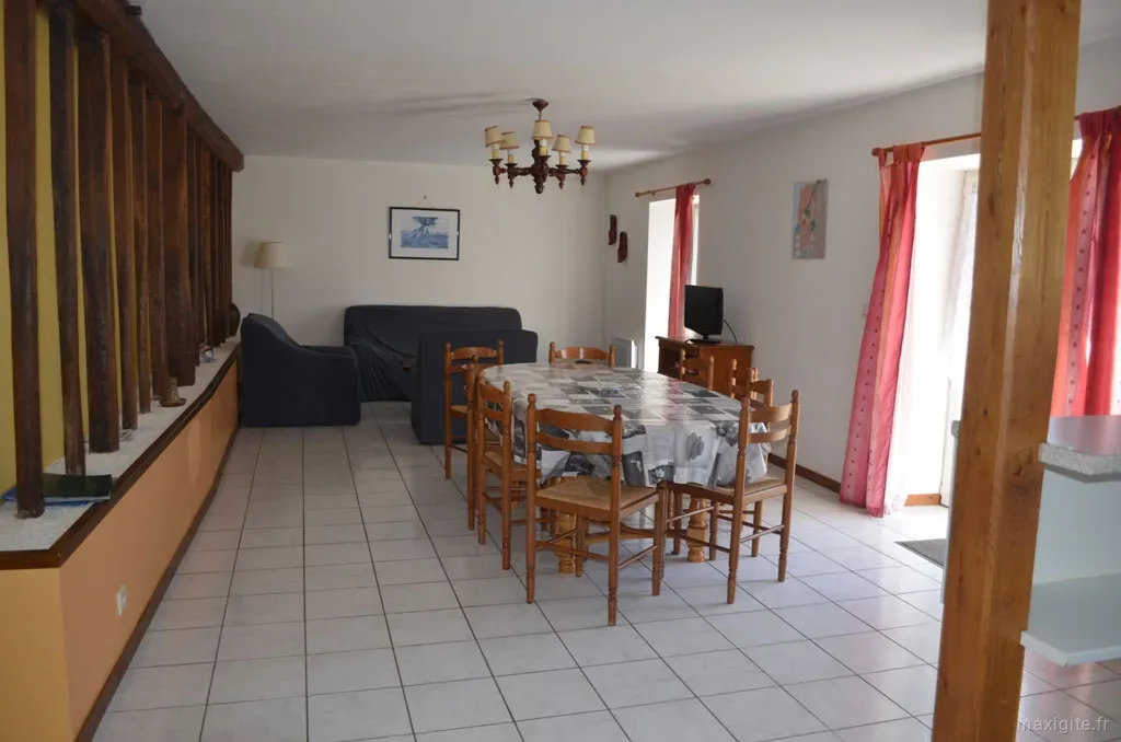 Salon avec canapés et grande table à manger en bois pour les repas de groupe