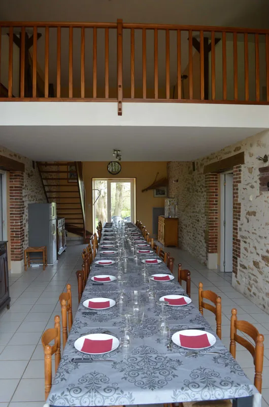 Grande salle à manger avec table dressée pour une vingtaine de convives et mezzanine