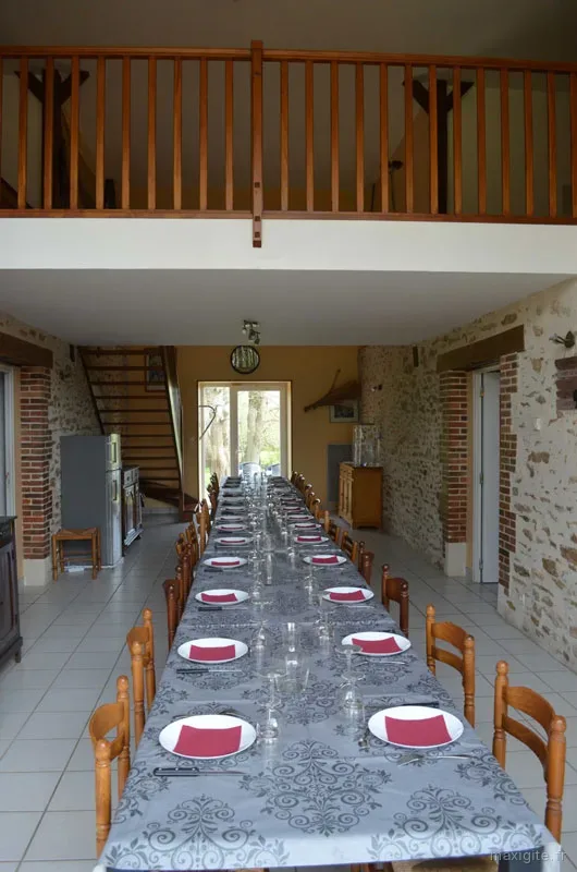 Grande salle à manger avec table dressée pour une vingtaine de convives et mezzanine
