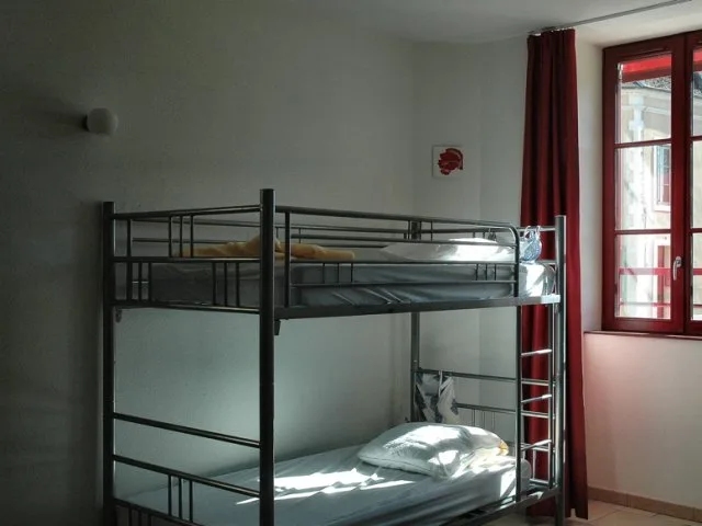 Cour intérieure sous arcade avec porte-fenêtre rouge et coin détente