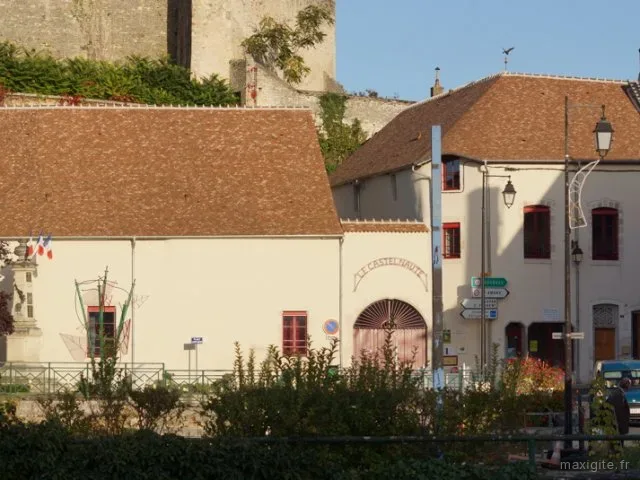 Façade en pierre du gîte au pied du château, entrée voûtée avec porte rouge
