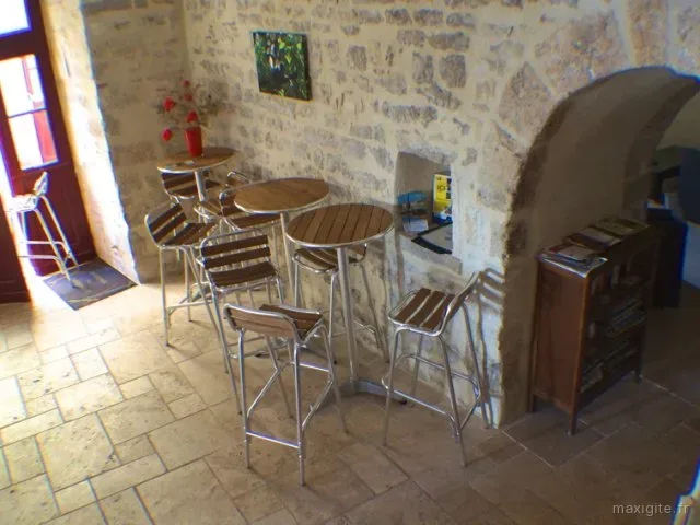 Espace bar avec mange-debout et tabourets contre un mur en pierres apparentes