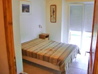 Chambre avec lit double et linge de lit à carreaux, fenêtre donnant sur l'extérieur