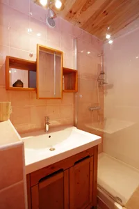 Salle de bain avec vasque en pierre, miroir en bois et paroi de douche vitrée