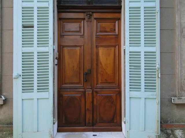 Entrée de la propriété avec grande porte en bois et volets bleu pâle