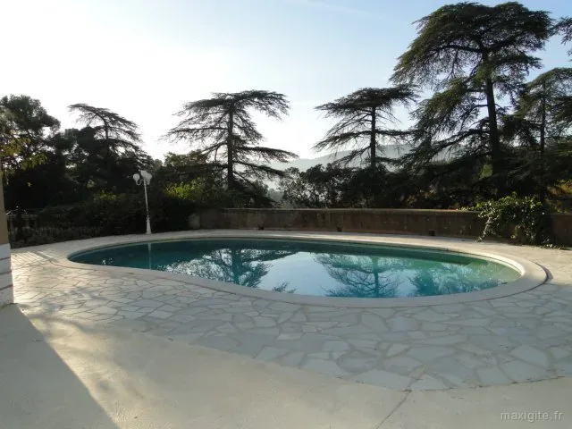 Façade de la bastide provençale avec porte-fenêtres vertes et arbres environnants