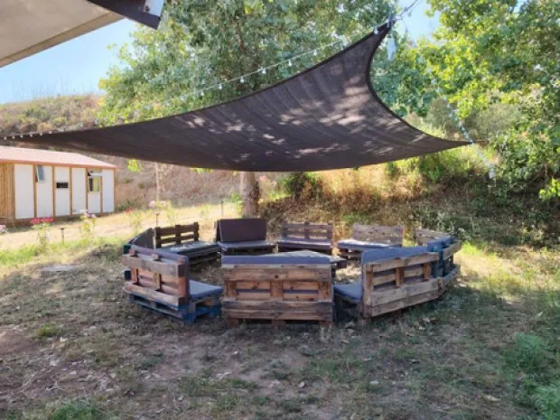 Espace détente extérieur ombragé avec assises en palettes de bois sous les arbres