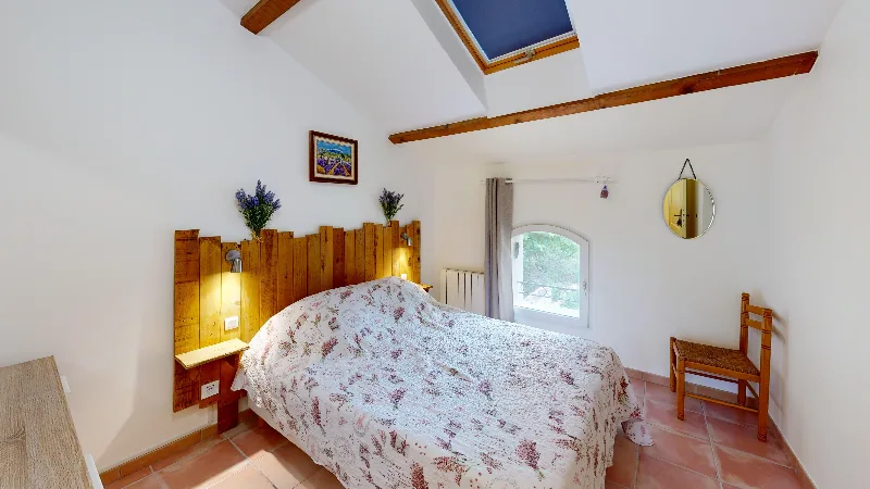 Chambre lumineuse avec lit double, tête de lit en bois et touches de lavande provençale