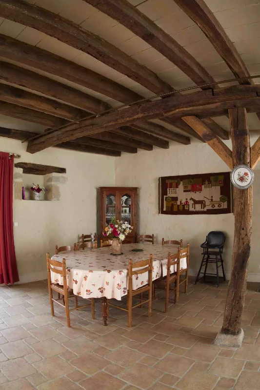 Grande salle à manger sous poutres apparentes avec table pouvant accueillir tout le groupe