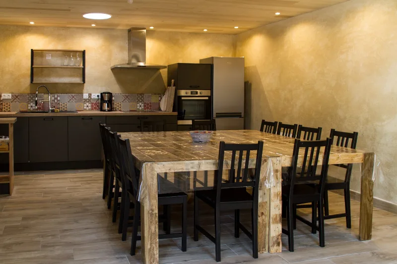 Cuisine équipée avec table en bois et chaises pour les repas de groupe