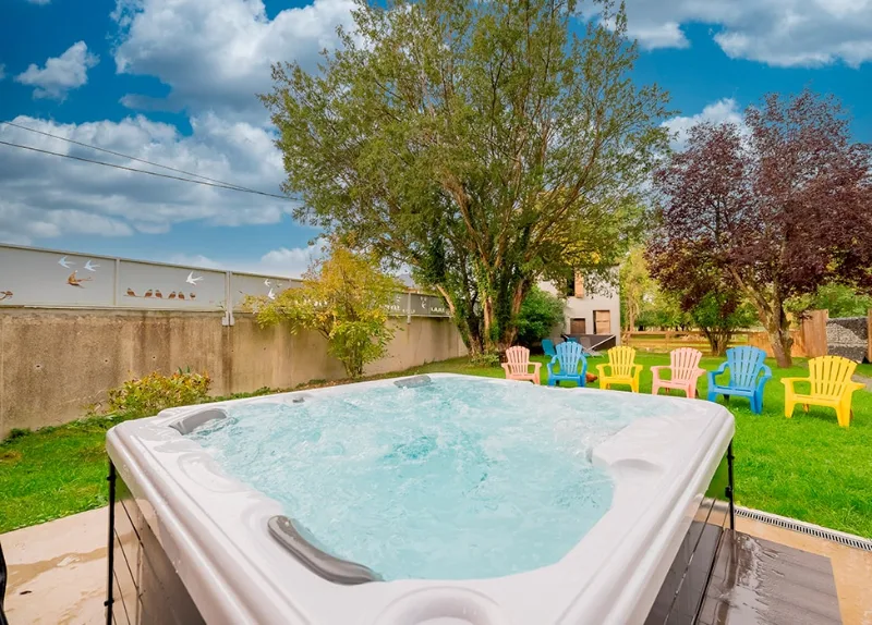 Spa extérieur privé chauffé avec vue sur le jardin et les chaises de couleur