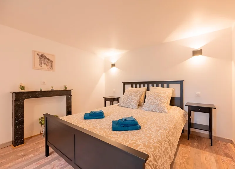 Chambre avec lit double, cheminée en marbre noir et decoration épurée