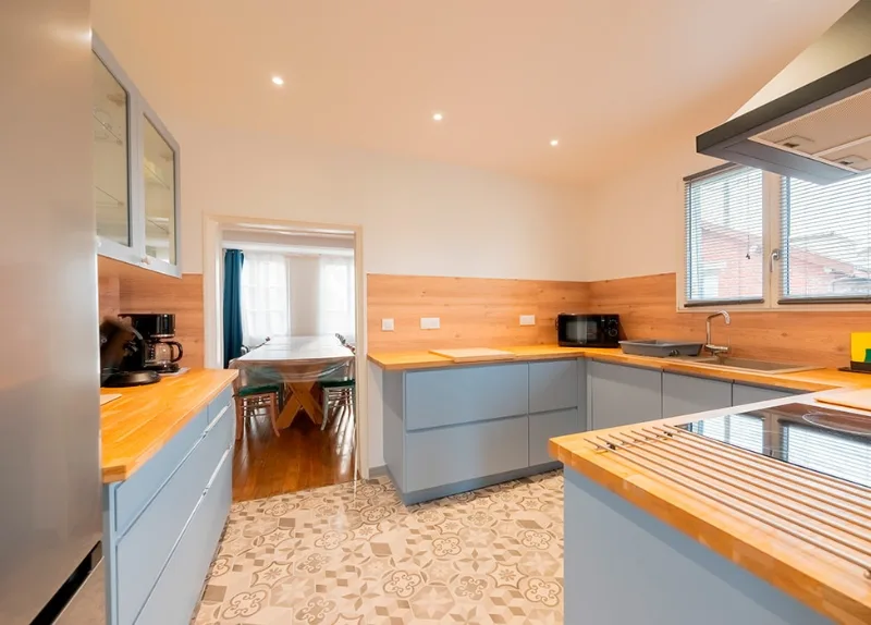 Cuisine équipée moderne avec plan de travail en bois et façades bleu gris