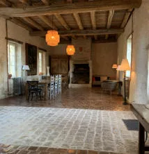 Grande salle à manger avec poutres apparentes, cheminée et table en pierre