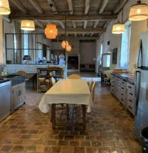 Cuisine ouverte de style ancien avec grande table centrale et suspensions lumineuses
