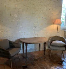 Coin salon avec fauteuils, table ronde et mur en pierres apparentes