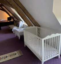 Chambre mansardée avec lits et lit bébé sous charpente