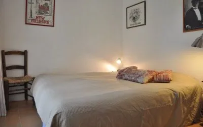 Chambre lumineuse avec lit double, poutre apparente et vue sur la terrasse