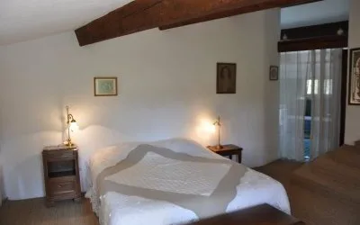 Chambre avec lit double sous plafond en pente et poutres en bois
