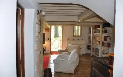Salon cosy avec fauteuils blancs, bibliothèque et poutres anciennes