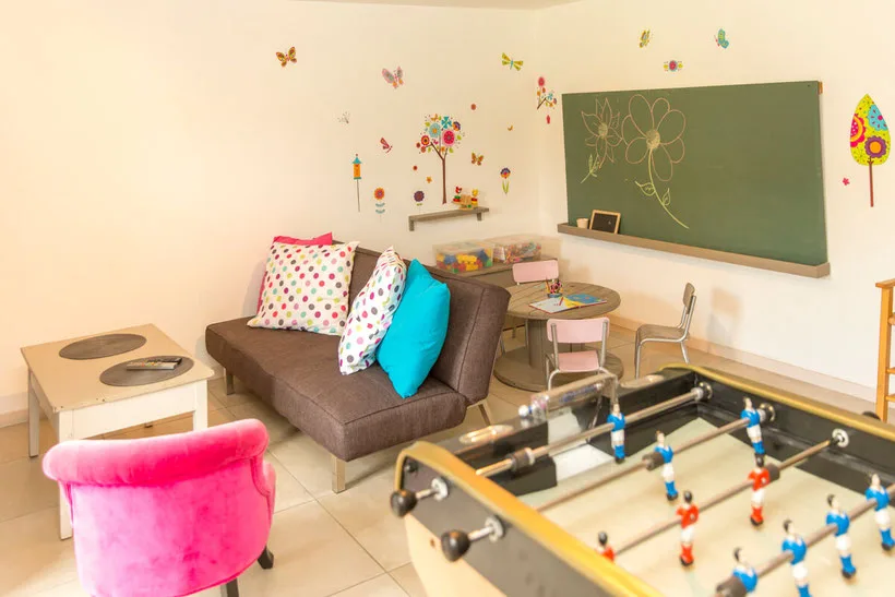 Salle de jeux pour enfants avec babyfoot, tableau et coin salon