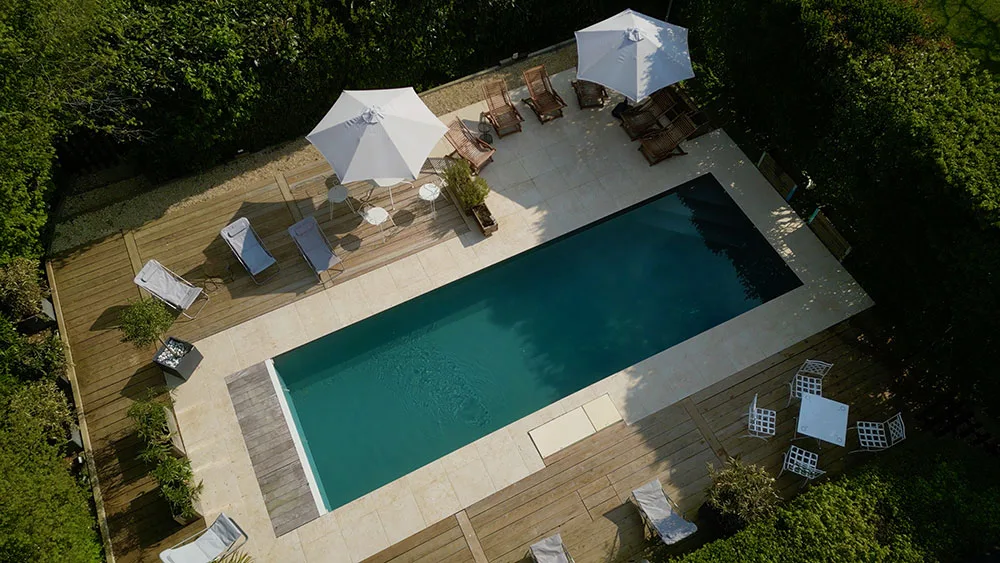 Vue aérienne de la piscine partagée entourée d'une terrasse en bois et de transats