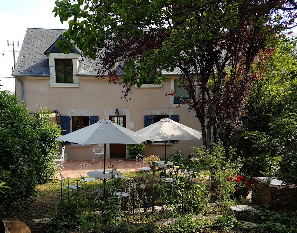 Façade de la maison Villa avec terrasse, tables et parasols dans le jardin arboré